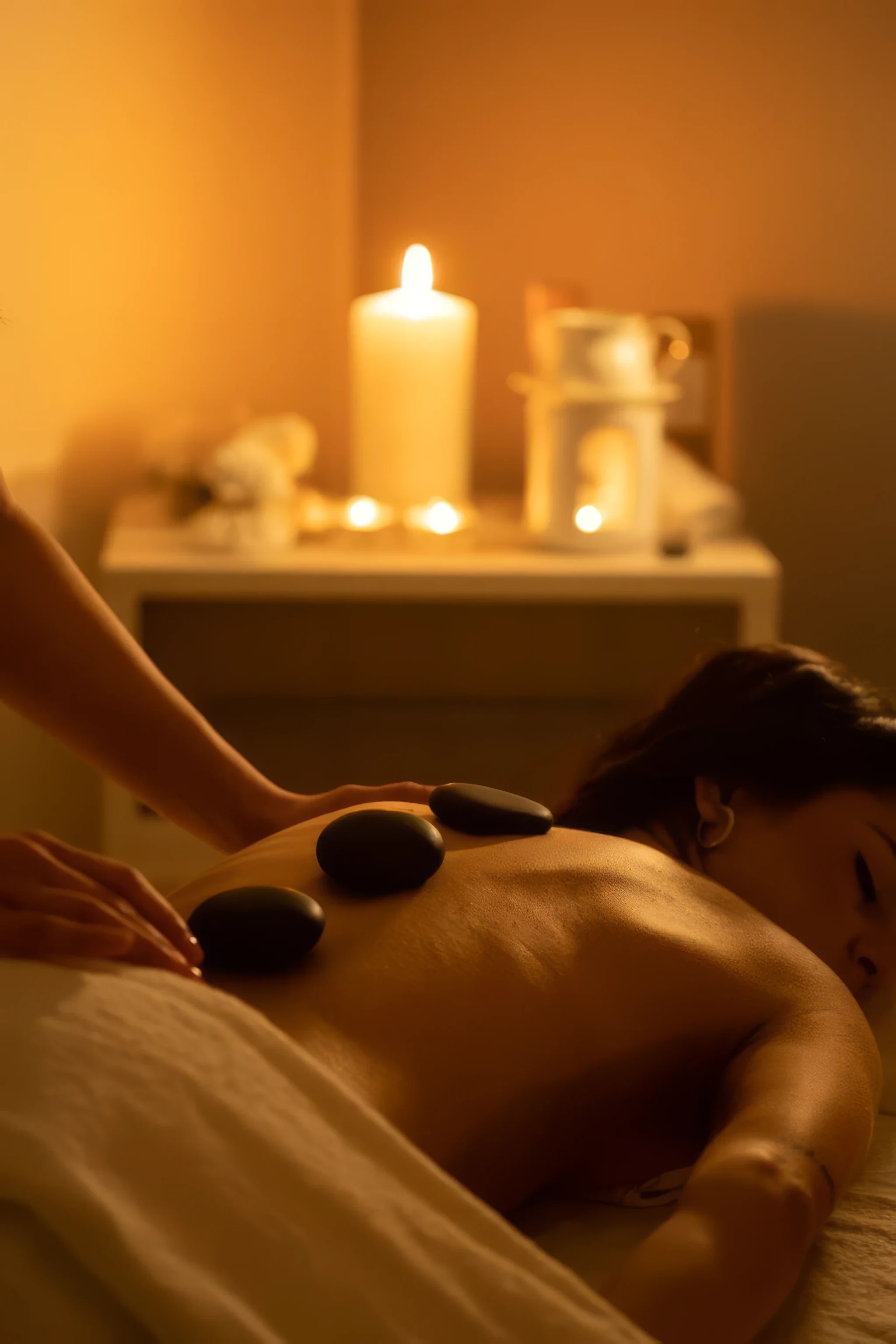 Massagem com pedras quentes num ambiente à luz de velas